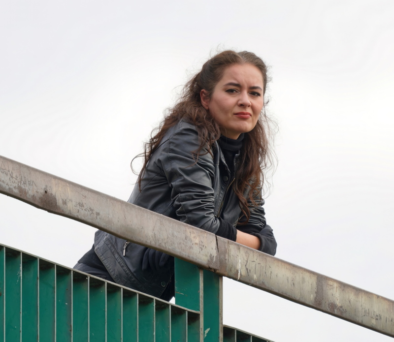 11 - Person in a black jacket leaning over a green railing